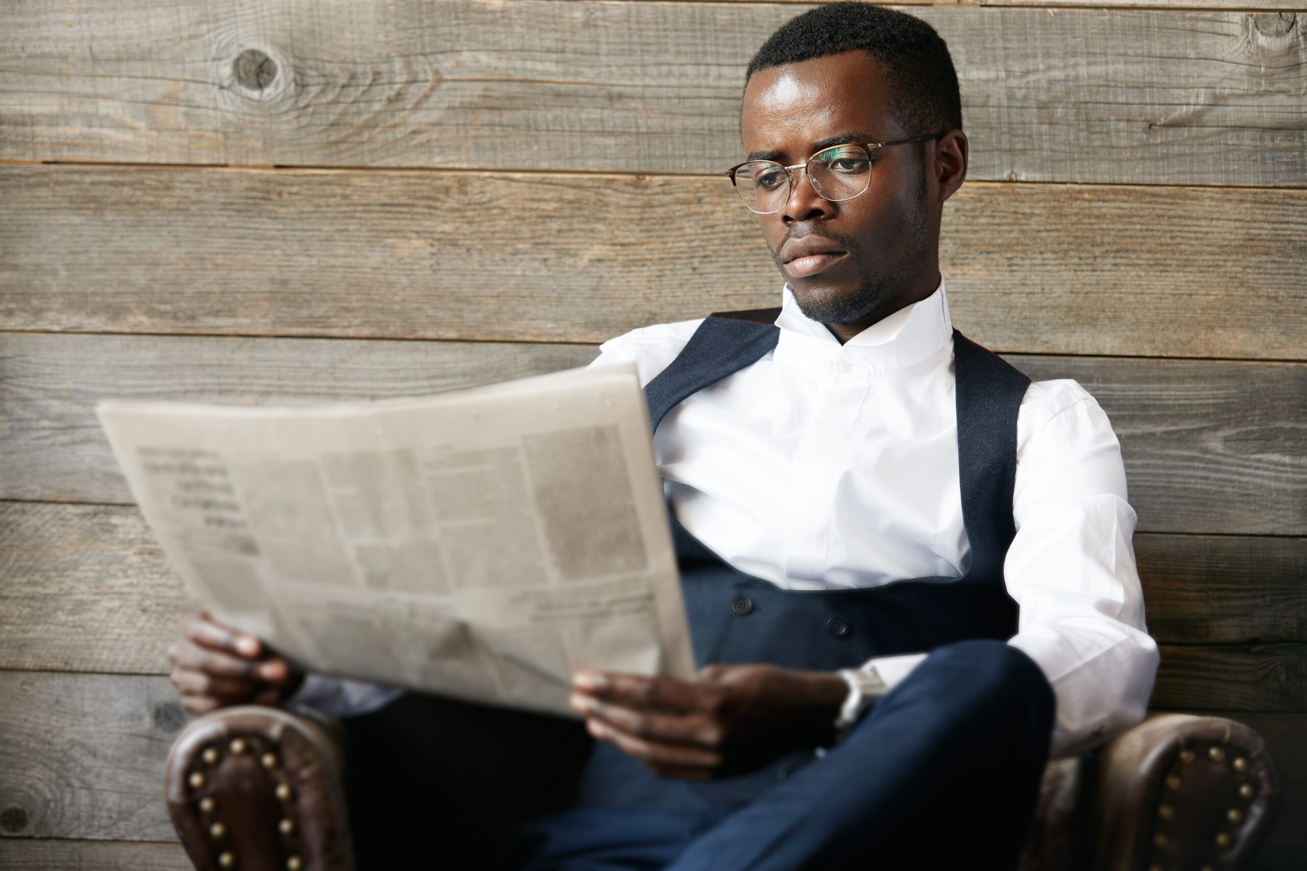 Businessman reading a newspaper while seated in an armchair